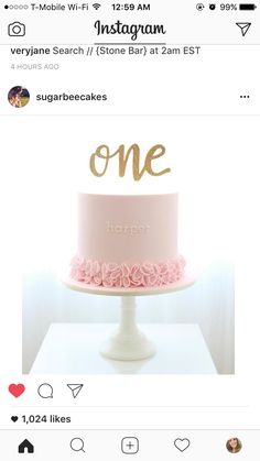 a pink and gold cake with the word'one'on it, sitting on top of a white pedestal