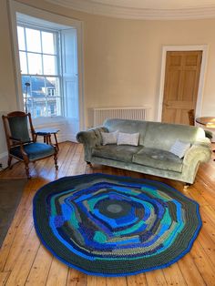 a living room filled with furniture and a rug on top of a hard wood floor