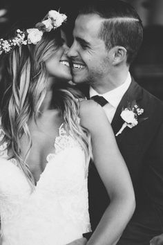 black and white photo of bride and groom smiling at each other with flowers in their hair