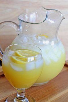 a pitcher and glass filled with lemonade sitting on a cutting board