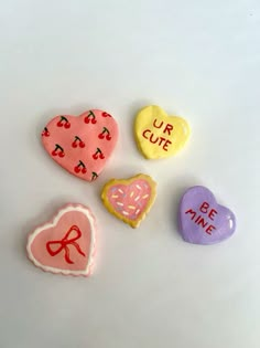 four heart shaped candies with the words our cute written on them, all in different colors