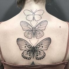 the back of a woman's neck with three butterflies on it