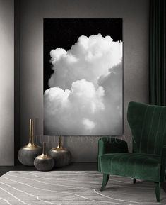 a green chair sitting in front of a black and white cloud painting on the wall