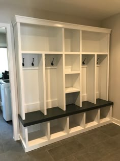 an empty room with white shelves and black benches