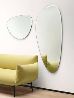 a yellow couch sitting next to a white wall with mirrors on it's sides