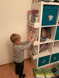 a little boy standing in front of a book shelf