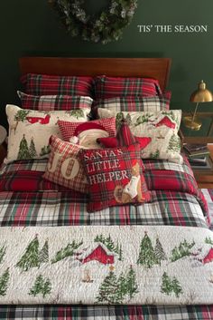 a bed with plaid comforter and pillows on top of it in front of a christmas wreath