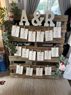 a wooden pallet with clothes pins and wedding date cards attached to the pegs