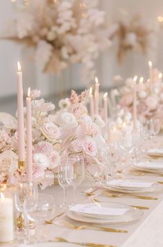 the table is set with white and pink flowers, gold rimmed glasses, and candles