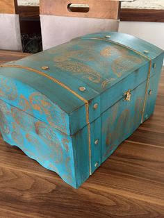 an old wooden box sitting on top of a wood floor next to a chair and table