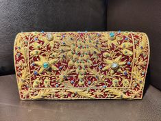 Beautiful hand-embroidered floral silk clutch bag inlaid with semi-precious stones. The front is completely covered in the design and has a closure flap with magnettic snap fastening. This clutch is perfect for daytime or night time. It is the ideal size for fitting all your essentials. It is a stylish accessory for each & every occasion. This equisite piece is even ideal for gifting to your near & dear one's . Thread - Silk Fabric - Velvet Variety of Semi-precious stones are used in this piece Zardozi is a type of heavy and elaborate metal embroidery on silk, satin, or velvet fabric base. Designs are often created using gold and silver wires and can incorporate pearls, beads, and precious stones. The embroidered silk clutch bag is made in Agra, India & is fully handmade. Designed to compl Rectangular Clutch With Gold Embroidery For Festivals, Rectangular Gold Embroidered Clutch For Festivals, Rectangular Gold Embroidery Clutch For Festivals, Traditional Embellished Clutch For Festivals, Traditional Embroidered Evening Bag For Formal Occasions, Traditional Embroidered Evening Bag For Formal Events, Traditional Embroidered Formal Evening Bag, Traditional Rectangular Evening Bag With Gold Embroidery, Traditional Gold Clutch With Gold Embroidery