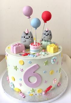 a birthday cake with two cats on top and balloons in the shape of number six