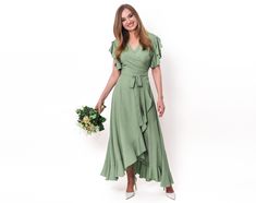 Step into the enchantment of our Sage Green Romantic Wrap Around Dress - a divine creation in light, natural fabric that promises grace and sophistication. This maxi dress, with its timeless allure, is a perfect choice for weddings, formal events, and those captivating evenings under the stars. Crafted for the modern romantic, this dress offers a perfect balance of comfort and elegance. The gentle sage green hue adds a touch of serenity to your presence, while the wrap-around design and short sl Summer Wedding Guest Midi Dress With Short Sleeves, Green Short Sleeve Evening Dress For Wedding, Spring Wedding Guest Maxi Dress With Short Sleeves, Chic Short Sleeve Midi Bridesmaid Dress, Elegant Maxi Wrap Dress For Garden Party, Formal Flowy Maxi Wrap Dress, Elegant Short Sleeve Bridesmaid Midi Dress, Green Short Sleeve Dress For Wedding, Flowy Wrap Dress For Evening In Summer