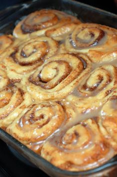 some cinnamon rolls sitting on top of a pan filled with brown sauce and melted chocolate