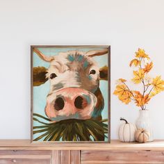 a painting of a cow with leaves on it's head is displayed in front of a dresser