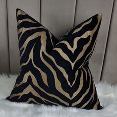 a black and gold zebra print pillow sitting on top of a white fur covered bed