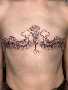 a woman's back with tattoos on her chest and two flowers in the center