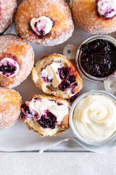 blueberry donuts with cream cheese and jam on a plate next to small bowls