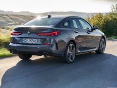 the rear end of a gray bmw vehicle driving down a road