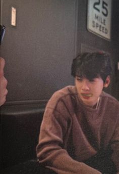 a young man sitting at a table with food in front of him and another person standing next to him