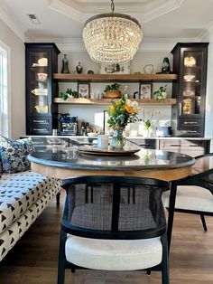 a dining room table with chairs and a chandelier hanging from it's ceiling