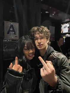 two people standing next to each other giving the peace sign