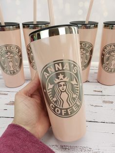 a hand holding a pink starbucks cup with six straws in front of it on a white table