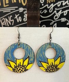 This is a pair of Handcrafted Woodburn 2.5" Sunflower earrings with blue and yellow paint and a yellow color wash tint. Nickelfree ear wires. Lightweight Sealed Artistic Blue Jewelry For Summer, Artsy Yellow Jewelry With Ear Wire, Artsy Yellow Earrings For Pierced Ears, Hand Painted Yellow Earrings For Summer, Artsy Hand Painted Yellow Jewelry, Blue Hand Painted Flower Earrings, Yellow Hand Painted Artsy Earrings, Hand Painted Yellow Artsy Earrings, Artistic Hand Painted Yellow Earrings