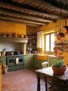 a kitchen with yellow walls and green cupboards, pots on the stove, and a wooden dining table