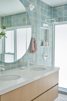 a bathroom with blue and white tiles on the walls, two sinks and a large mirror