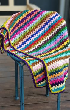 a multicolored crocheted blanket sitting on top of a blue metal chair