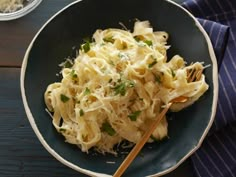 a black bowl filled with pasta and parmesan cheese