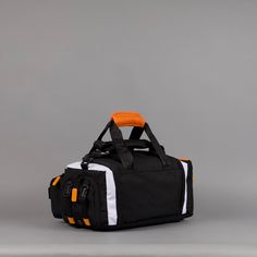 an orange and black duffel bag sitting on top of a gray floor next to a white wall