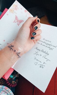 a woman's arm with a tattoo on it and a birthday card in front of her