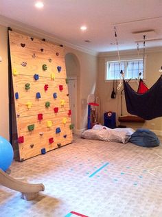 a room with climbing wall and hammock hanging from the ceiling