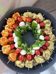 a platter with skewered vegetables and meats arranged in the shape of a wreath