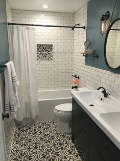 a white toilet sitting next to a bath tub under a bathroom mirror above a sink