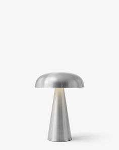 a silver table lamp on a white surface with the light turned off and dimming