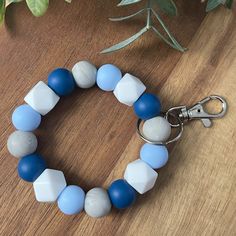 a blue and white beaded bracelet on a wooden table next to a potted plant