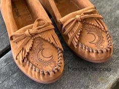 These hardsole moccasins are made by the brand Minnetonka; I free-hand etched them with original designs! The shoe features soft suede leather, a padded insole, and a lightweight but durable rubber sole.  Fit: runs a full size large  The shoes in the featured picture are in the color BROWN Hi! My name is Merche and I've been a henna artist since 2013. I discovered my skills are transferable to another awesome form of art...leather pyrography! As each pattern is drawn freehand, every shoe is slightly unique and one-of-a-kind. All patterns are Merche Mariposa originals, designed by me!  Have an excellent idea of your own? Send me a message. I absolutely love custom orders! www.etsy.com/listing/1351693619 Need it sooner? Rush order fee:  https://www.etsy.com/listing/1351277684/rush-order-fee Leather Pyrography, Ranching Life, Native American Moccasins, Moccasin Pattern, Wolf Paw, Moccasins Women, Leather Moccasins, Henna Artist, Free Hand