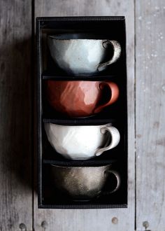 three cups in a black box on a wooden table