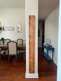 a tall wooden ruler sitting on top of a hard wood floor next to a dining room table