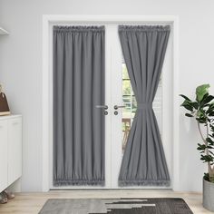 a white door with two gray curtains and a potted plant on the floor next to it