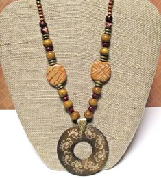 Wood Pendant Necklace on Waxed Linen Cord  16 to 21 inches (or shorter on request) with 2 inch round pendant They say if you can remember the Sixties, you weren't there. But I was there, and I do remember the fabulous, fun, tribal style jewelry that was popular then - and it's quite trendy today!  This red and brown pendant necklace features: * 2 inch round dark brown wood pendant covered with light tan symbols * anti-tarnish brass bail * dark brown waxed linen cord  * gorgeous golden tan Kazuri beads painted with white and red designs * wood beads in various sizes and tones * glass pearls in deep red * antiqued gold metal spacers * Nunn Design antiqued gold plated textured jump rings * gold plated chain * gold plated lobster claw clasp This bohemian jewelry can be worn at anywhere from 16 Brown Amulet Necklaces With Large Beads, Traditional Brown Beaded Necklace With Multicolored Beads, Brown Large Beads Jewelry For Festivals, Traditional Brown Beaded Necklace With Colorful Beads, Handmade Brown Beaded Necklaces For Festivals, Brown Large Beaded Jewelry For Festivals, Bohemian Brown Beaded Necklaces For Festivals, Brown Bohemian Beaded Necklaces For Festivals, Brown Beaded Amulet-style Jewelry