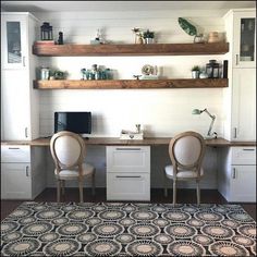 two chairs sitting at a desk with shelves above it and a rug on the floor