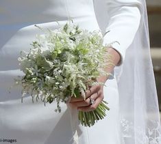 a close up of a person wearing a wedding dress and holding a bouquet with white flowers