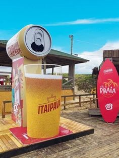 there is a tall glass with beer in it on the wooden platform next to some surfboards