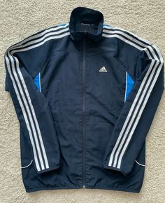 Adidas Blue Outerwear With Three Stripes Branding, Adidas Blue Outerwear With Three Stripes, Blue Hooded Outerwear With Three Stripes, Adidas Long Sleeve Track Jacket With Three Stripes, Sportswear Windbreaker With Three Stripes, Long Sleeve Windbreaker With Three Stripes, Adidas Blue Track Jacket With Three Stripes, Adidas Long Sleeve Outerwear With Three Stripes, Adidas Long Sleeve Windbreaker With Three Stripes