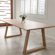 a wooden table sitting in the middle of a room with white shutters on the windows