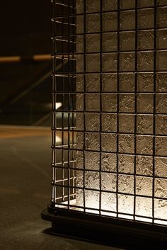 a light that is on in front of a metal caged structure at night time